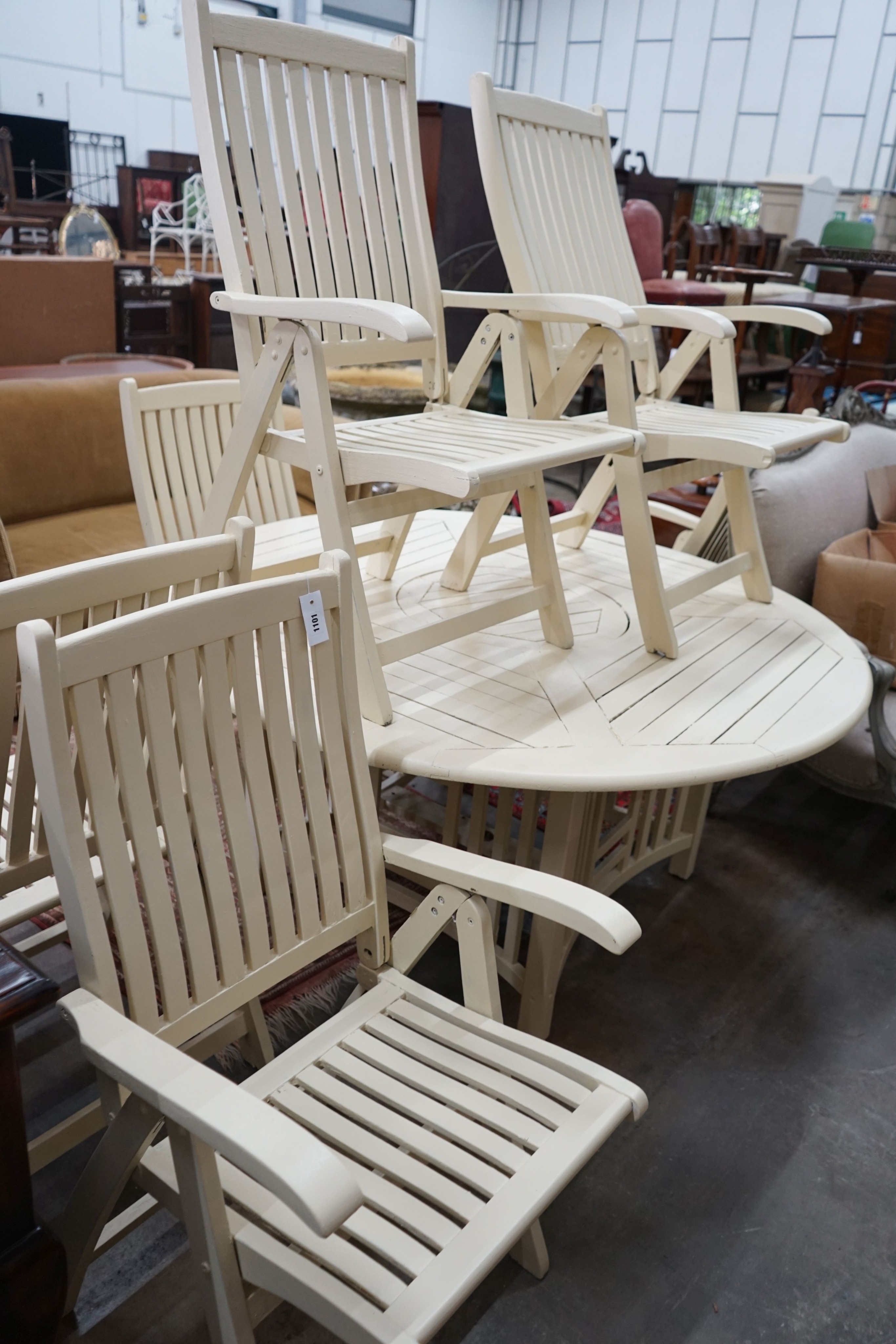 A circular painted teak garden table, diameter 150cm, height 72cm and six folding elbow chairs